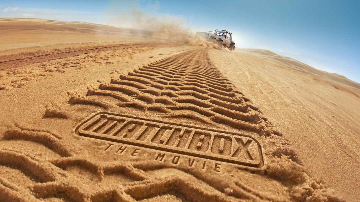 Matchbox The Movie logo pressed into desert tire tracks with a vehicle in the distance